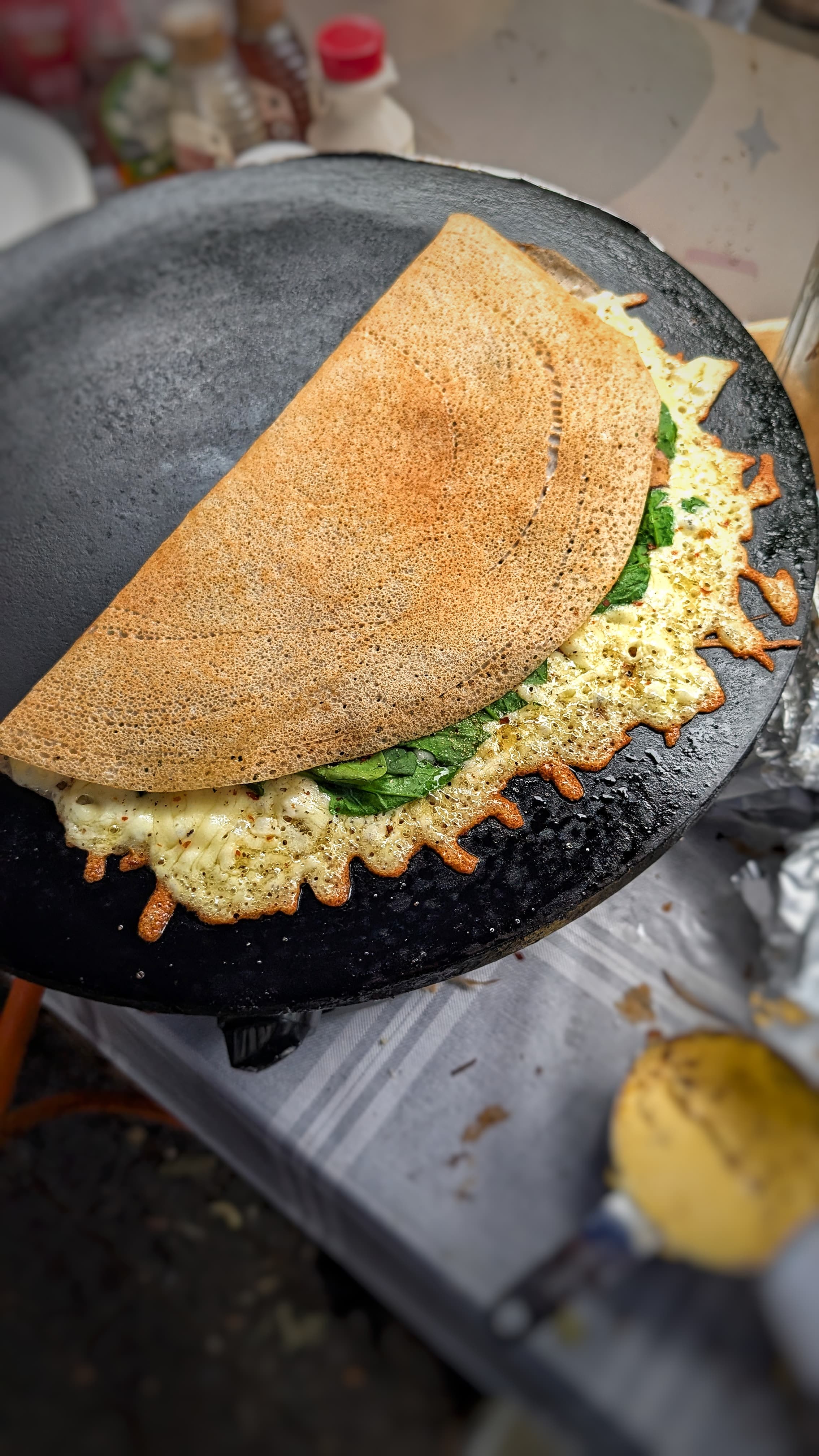 Buckwheat crêpe folded in half on the stone billig, fresh spinach and egg peeking from the fold